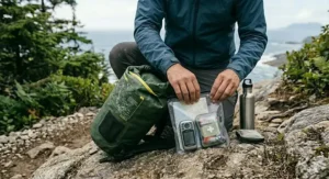 Hiker filling a dry bag with essential supplies for a day trip in the Rockies.