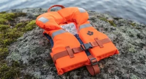 Detailed view of safety features including a head-support collar and leg straps on an infant kids PFD for canoe camping.