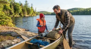 A family organizing dry bags and a bright kids PFD for canoe camping inside a Kevlar canoe on a rocky shore.