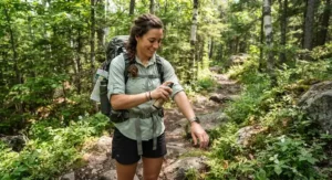 A hiker applying natural bug repellent for camping before exploring an Ontario provincial park trail.