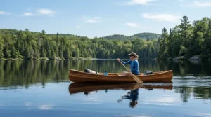 Paddling a canoe through remote wilderness waters while wearing gear to help choose the right bug jacket vs head net for fishing.